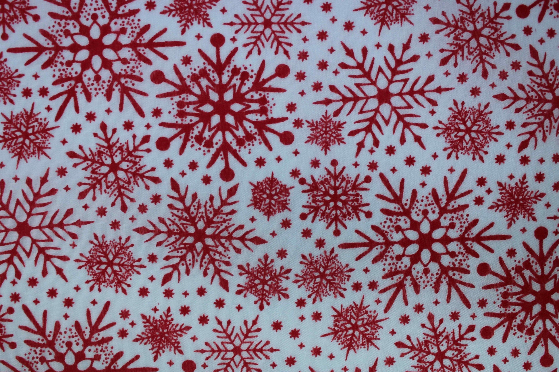Various red snowflake designs on white background fabric