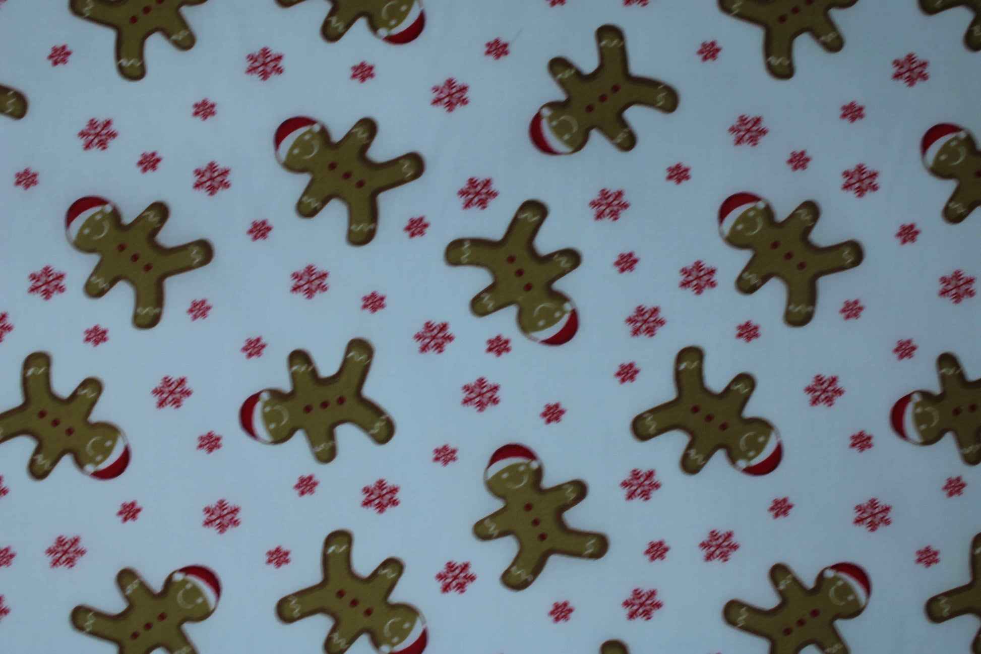 smiling gingerbread men with Xmas hat on white fabric with red snowflakes detail