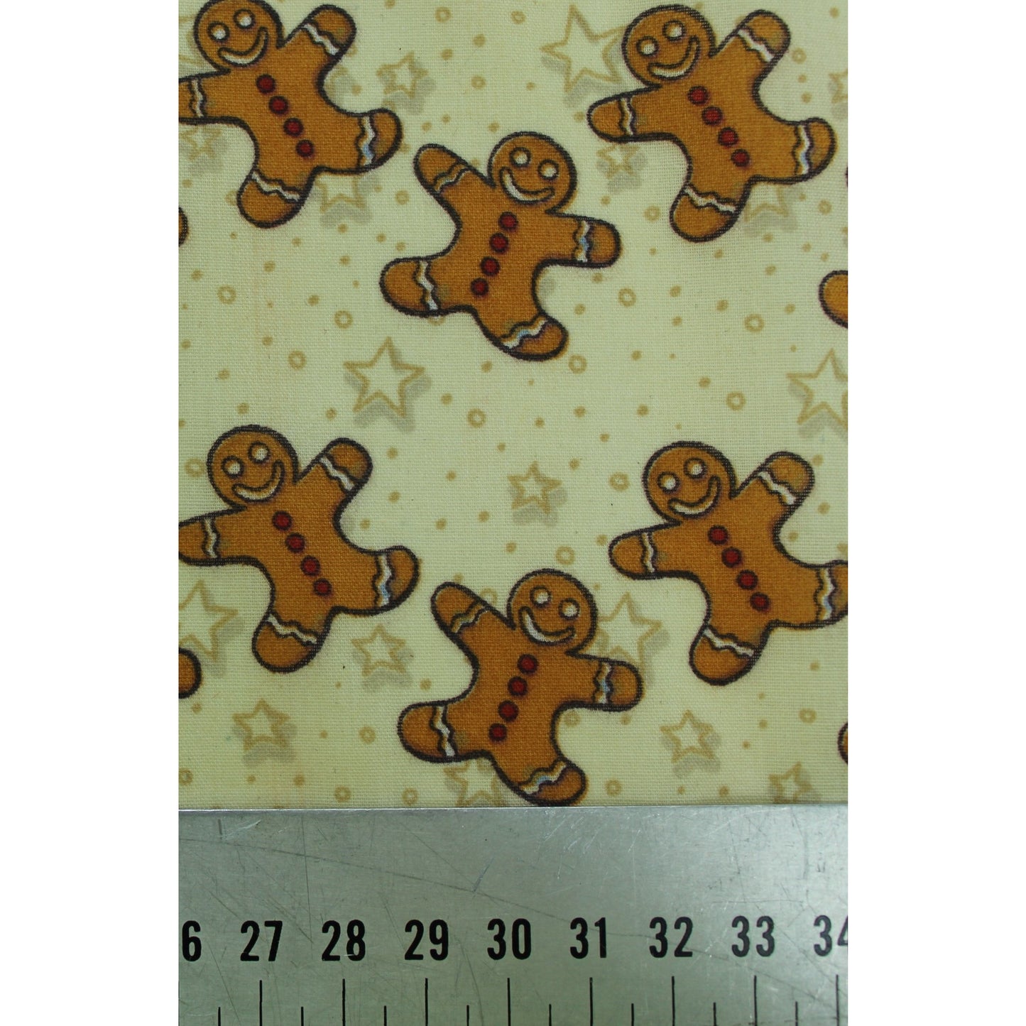 smiling gingerbread men in tan colour on a pale yellow background with stars and dots polycotton fabric